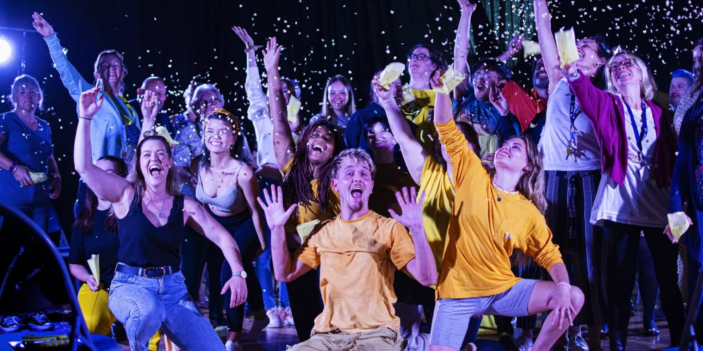 A group of young people celebrating, with confetti in the air and lots of smiling