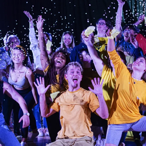 A group of young people celebrating, with confetti in the air and lots of smiling
